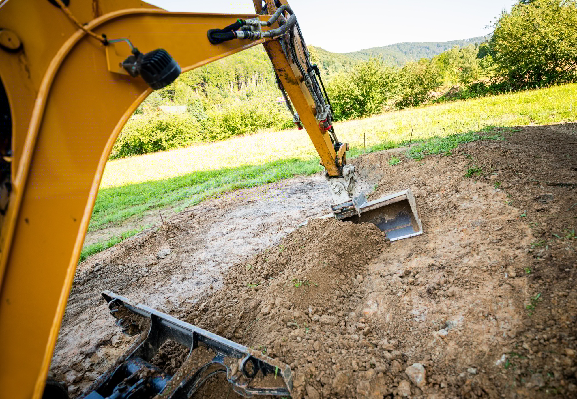 Mini excavator digging preparing ground under home garden