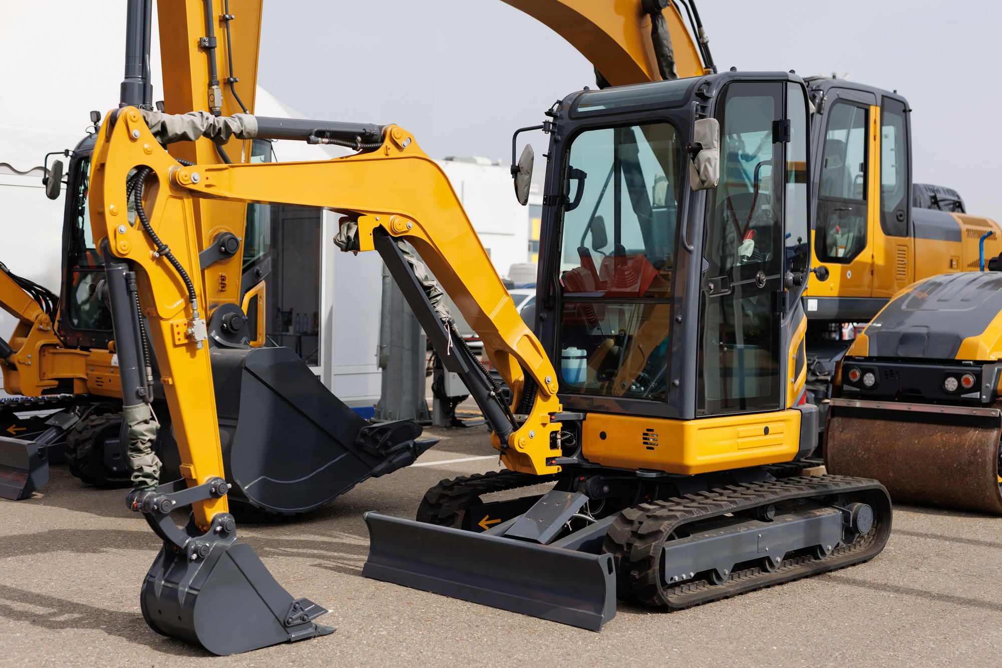 New mini excavators in the same row in the agricultural machinery store. New mini excavators in the same row in the agricultural machinery store.