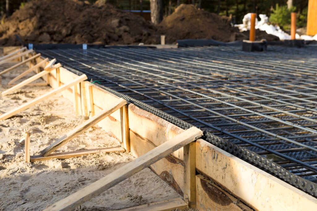 Iron fittings on a wooden formwork with laid pipes are the basis for pouring the foundation